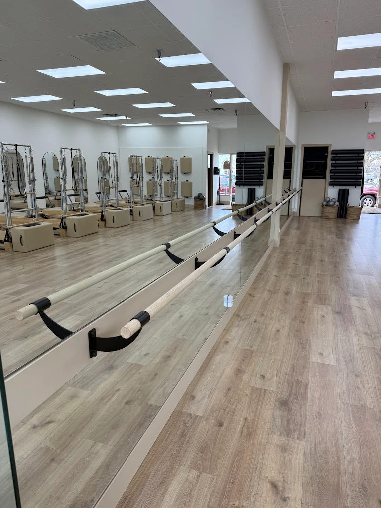 Barre class at a wooden ballet barre in a neutral studio